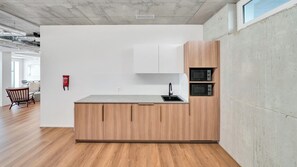 A modern kitchen with wooden cabinets, a grey countertop, and built-in appliances. - Mooi Apartments Biel (Biel)