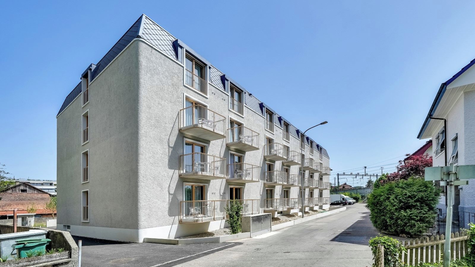Een meerlaags woongebouw met balkons en een schuin dak.