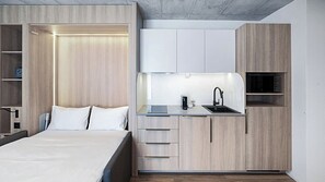 A compact bedroom with a bed, bedside table, and a built-in wardrobe. - Mooi Apartments Biel (Biel)