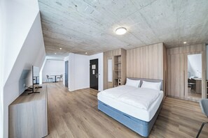 A modern bedroom with a large bed, built-in wardrobe, and a desk area. - Mooi Apartments Biel (Biel)