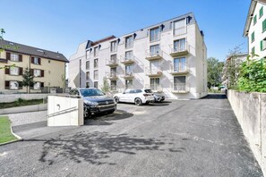 A multi-story residential building with balconies, a parking area with two cars, and a clear sky. - Mooi Apartments Biel (Biel)