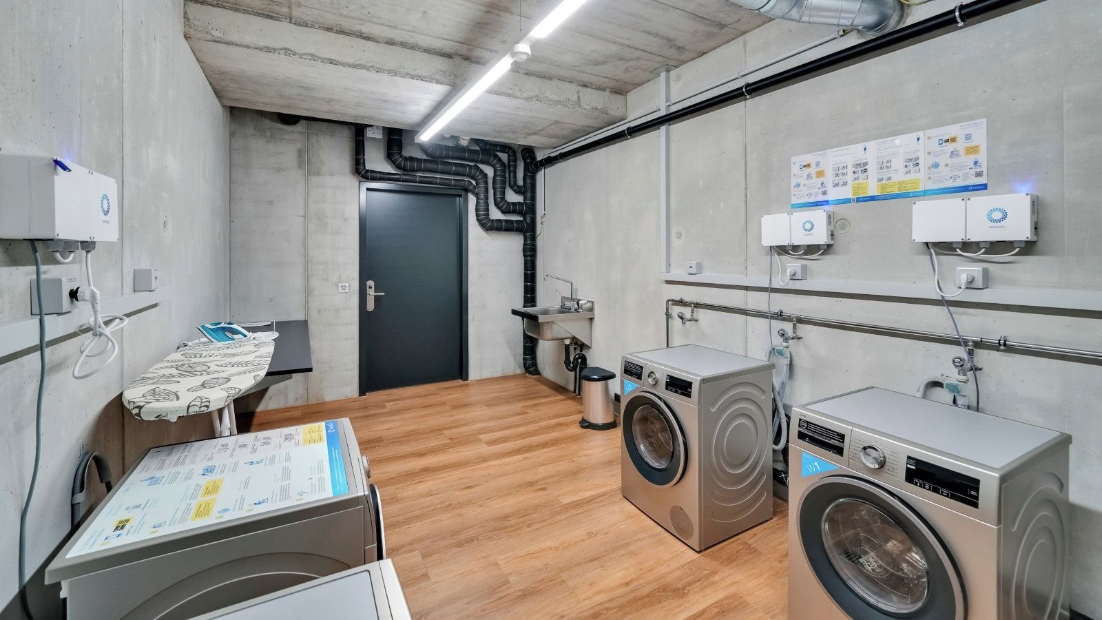 Une buanderie équipée de deux machines à laver, d’un étendoir et d’un radiateur fixé au mur.