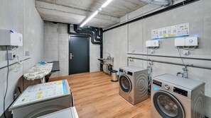 A laundry room with two washing machines, a drying rack, and a wall-mounted heater. - Mooi Apartments Biel (Biel)