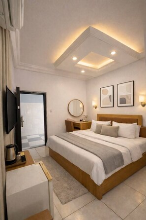 Une chambre d’hôtel moderne dotée d’un grand lit, de tables de chevet, d’une télévision et d’un plafond équipé de luminaires encastrés.