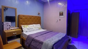 Un dormitorio con cama, mesita de noche, silla, escritorio y espejo.