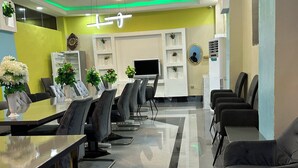 Una sala de conferencias moderna con una larga mesa, varias sillas y una televisión.