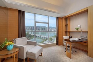 Habitación de hotel con una ventana grande, un sofá, un escritorio y una silla.
