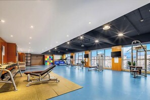 A gym with exercise equipment, a blue floor, and large windows. - Huatian Hotel (Zhangjiajie)