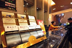 Un comptoir d’accueil avec des brochures d’information et un écran numérique en arrière-plan.
