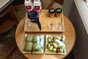 A wooden tray with condiments, a black object, and two bags of fruits on a round table. - Huatian Hotel (Zhangjiajie)
