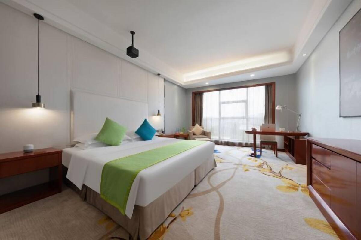 Una habitación de hotel con una cama grande, mesitas de noche, un escritorio y una silla.