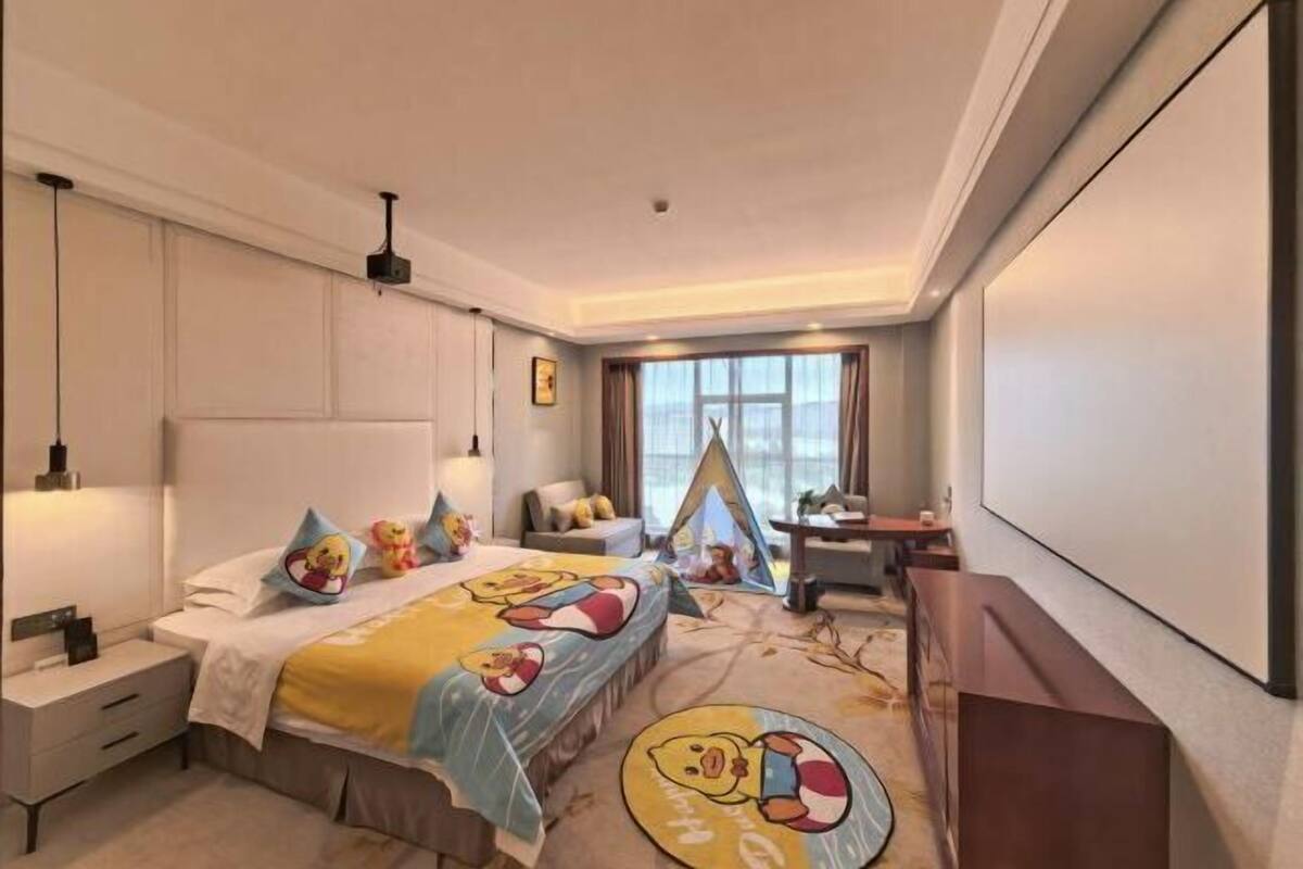 Una habitación de hotel con cama, mesitas de noche, escritorio, silla, ventana y una estructura tipo tienda de campaña.