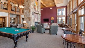 Un grand espace intérieur comprenant une table de billard, des sièges confortables et une cheminée en pierre.