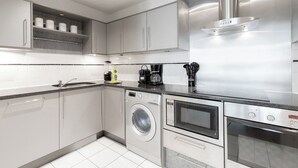 Una cocina moderna con electrodomésticos de acero inoxidable, lavadora integrada, horno y microondas.