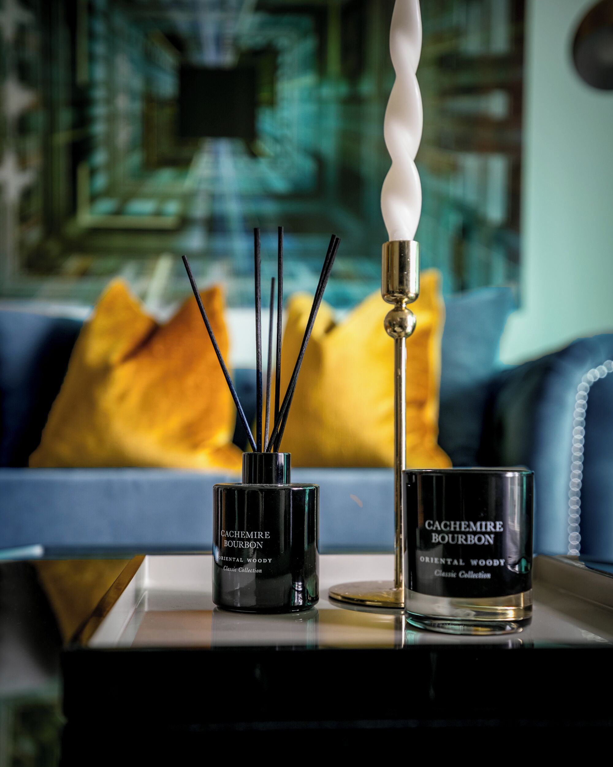 Un soggiorno moderno con un divano blu, una candela decorativa e una bottiglia di CACHEMIRE BOURBON.