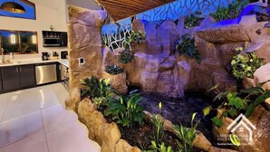 Cozinha moderna com uma cascata de pedra, área de refeições e teto com textura de madeira.
