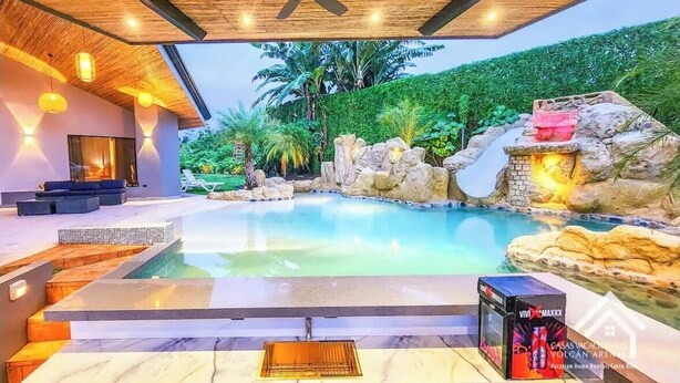 Uma área de piscina moderna com vista desimpedida, um ventilador de teto e uma estrutura de pedra.