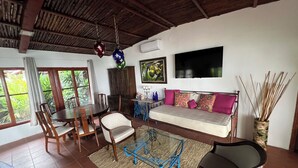 A living room with a wooden ceiling, a sofa, a dining table with chairs, and a TV mounted on the wall. - B&B Casa Naturaleza Playa Corona (Las Uvas)