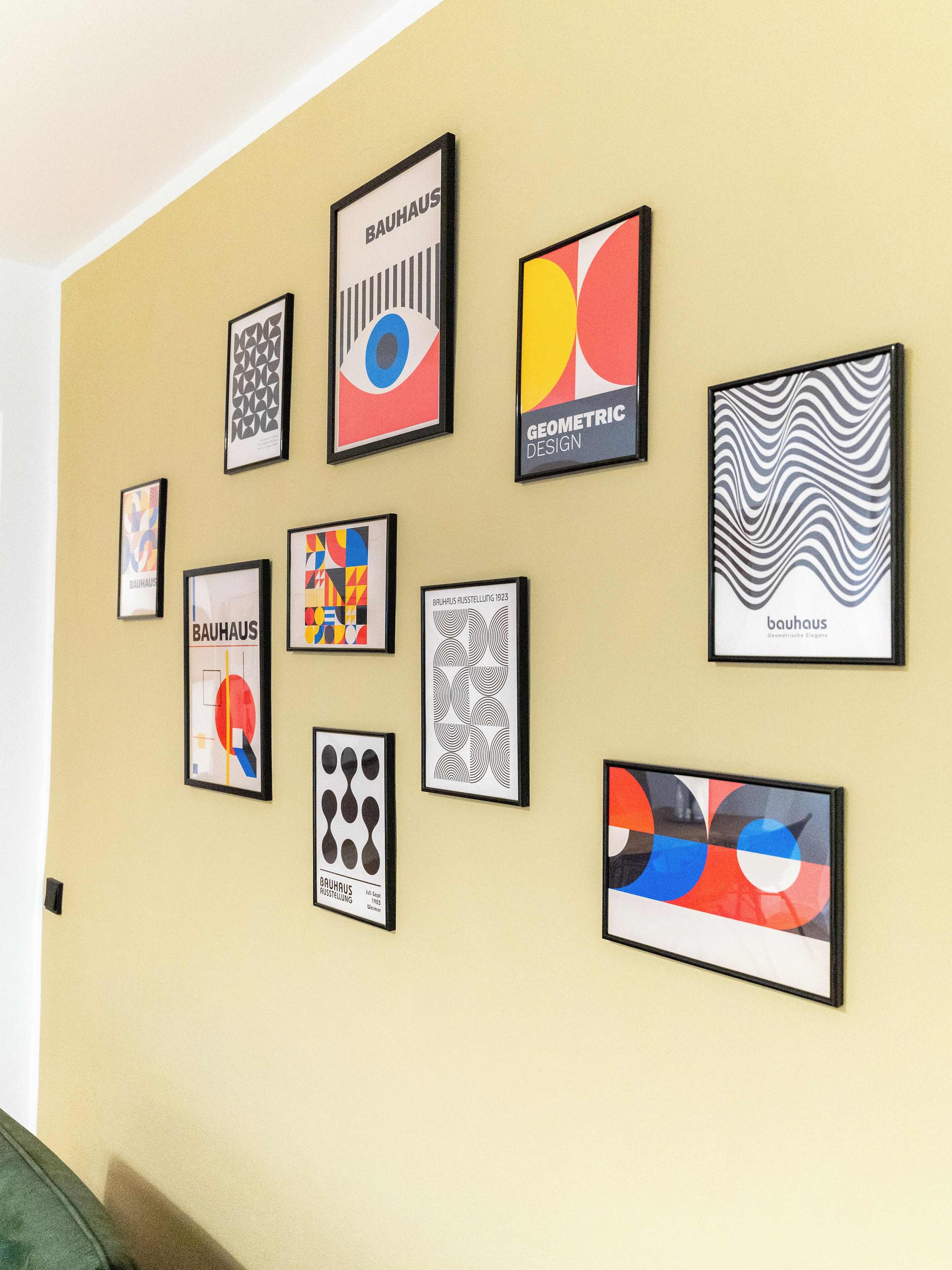Un mur orné de divers tableaux encadrés, comprenant des motifs géométriques et des compositions abstraites.