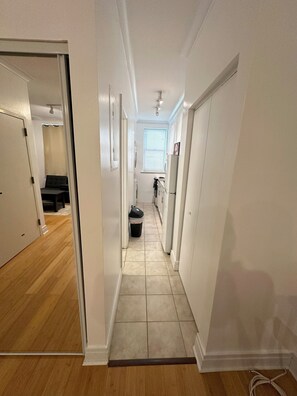 Leading to a kitchen area with a refrigerator and cabinets.