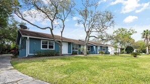 Une rangée de maisons de plain-pied, avec une pelouse bien entretenue et de grands arbres.