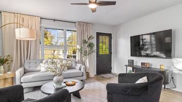 A modern living room with a sofa, armchairs, a coffee table, and a TV.