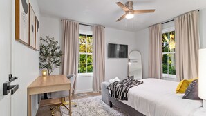 Un dormitorio moderno con cama, escritorio, silla y ventilador de techo.
