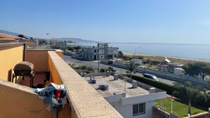 A balcony with a view of a coastal road, buildings, and a beach. - Apartment in front of the sea (Siderno)