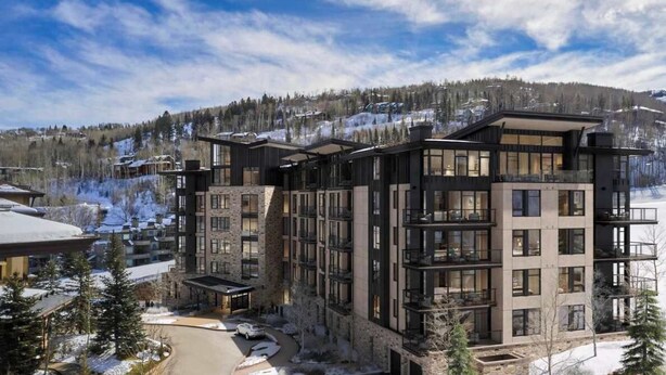 A modern multi-story hotel with a stone facade, large windows, and balconies.