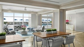 A spacious indoor area with a pool view, featuring a wooden table, white chairs, patterned sofas, and a ceiling fan. - Unforgettable Family Fun at Marriott’s BeachPlace Towers- 2 Bedroom Villa (Fort Lauderdale)