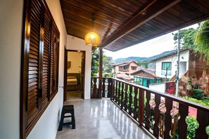 A balcony with a wooden railing, a hanging light fixture, and a view of surrounding houses. - TuriHouse (Angra dos Reis)