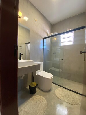 A modern bathroom with a glass shower enclosure, a white toilet, and a sink. - TuriHouse (Angra dos Reis)