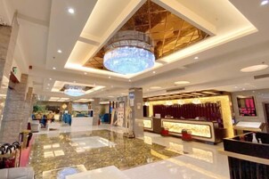 Un hall de hotel con mostrador de recepción, zona de estar y una araña.