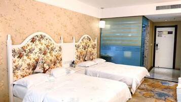 Quarto de hotel com duas camas, cabeceiras florais, uma janela grande com vista e uma porta com um aviso.