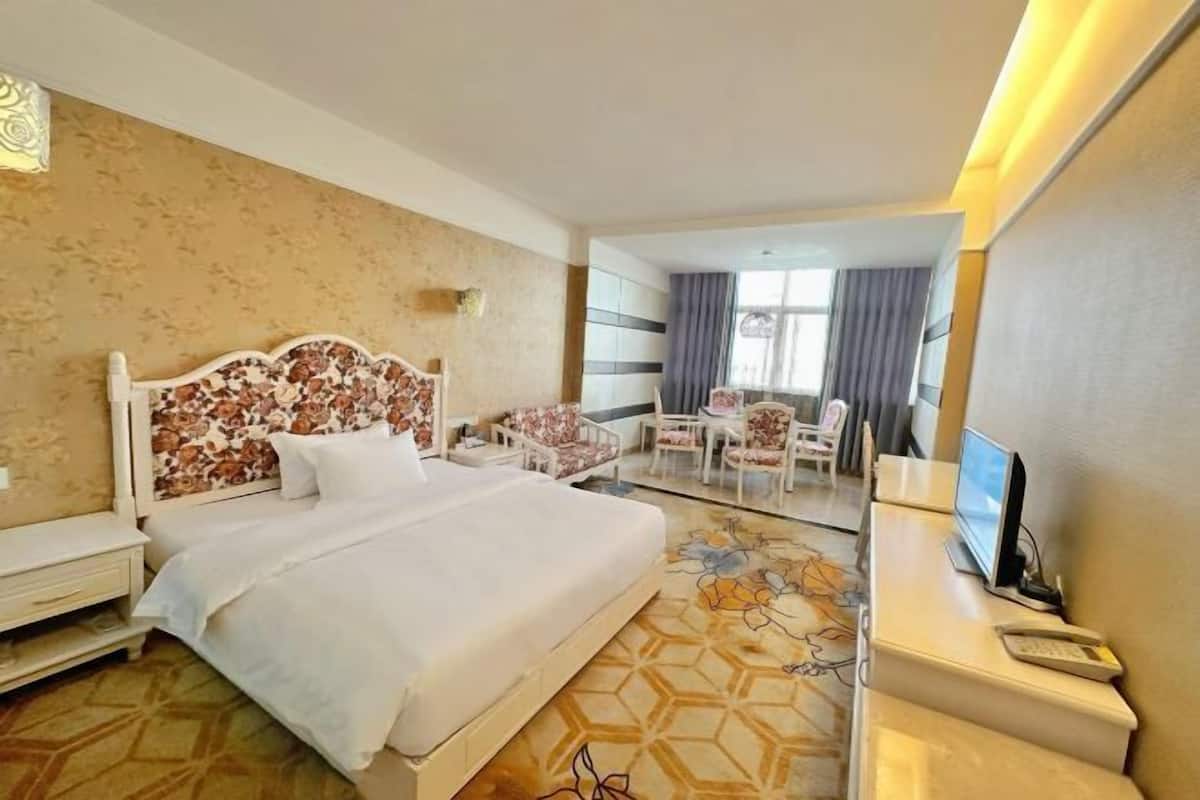 Habitación de hotel con una cama grande, un escritorio con computadora, una silla y una mesita.