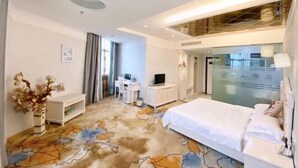 Ein Hotelzimmer mit einem Bett, einem Schreibtisch mit Computer, einem Fernseher und einer dekorativen Vase.