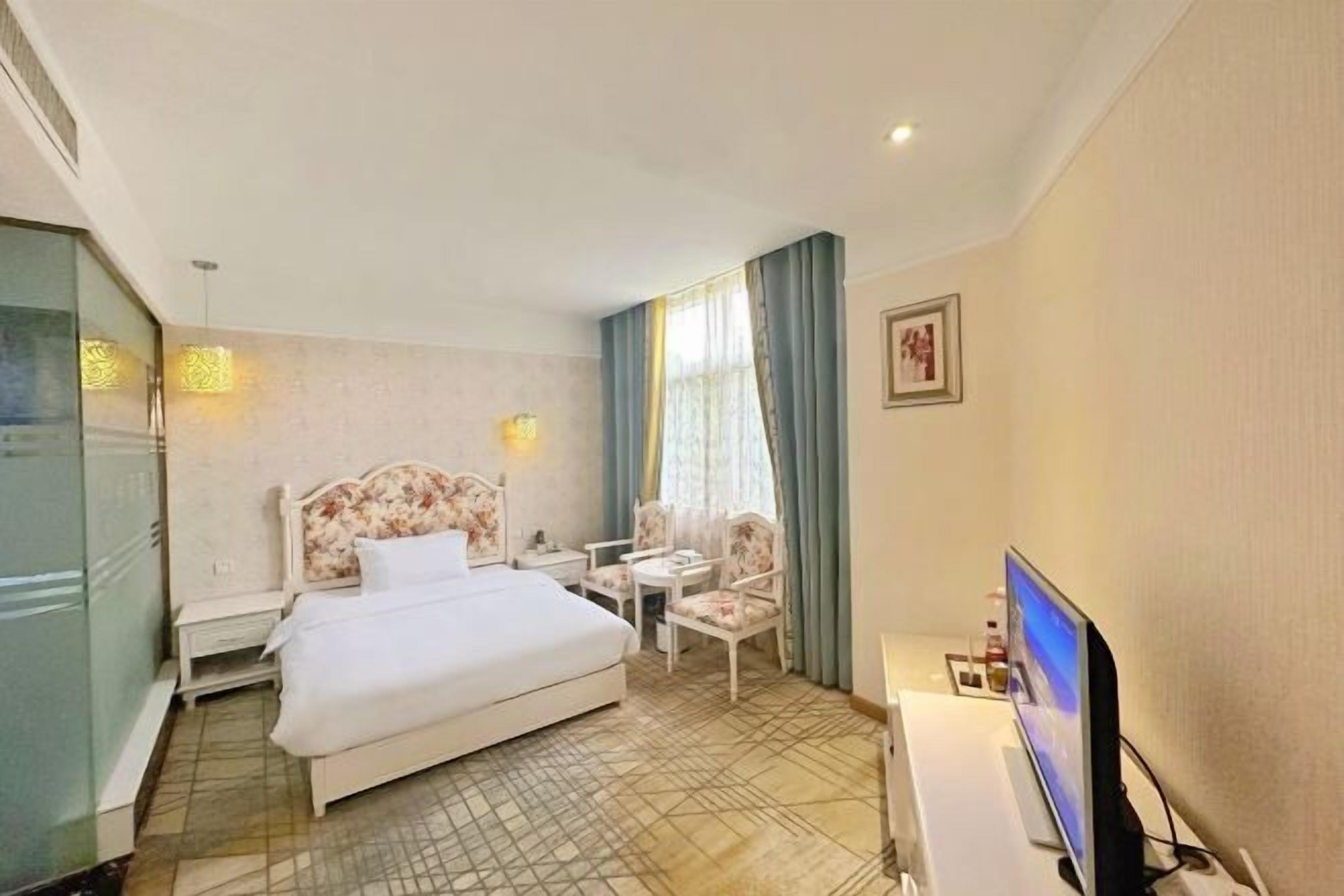 Een hotelkamer met een bed, een bureau met een computer, een stoel en een televisie.