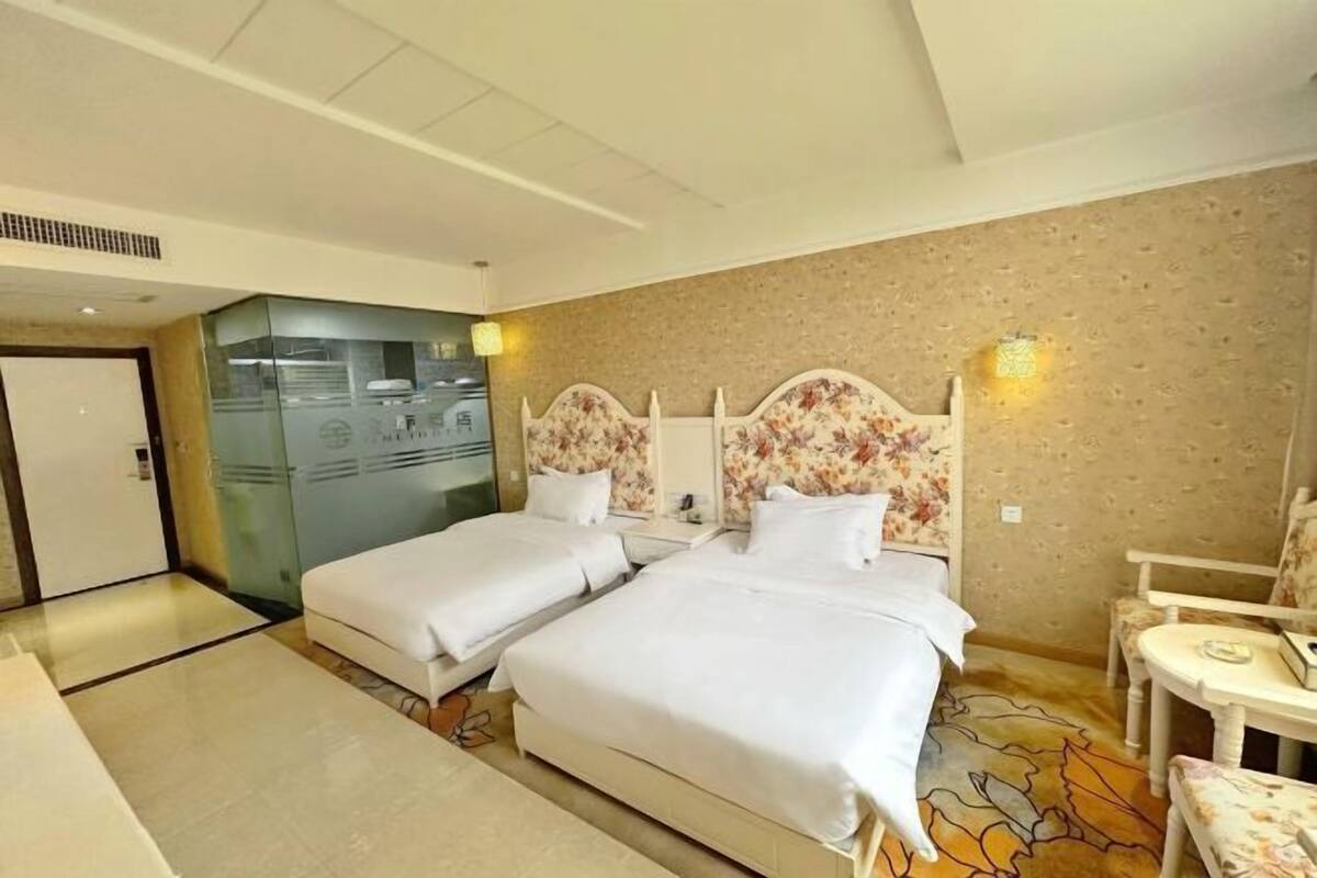 Habitación de hotel con dos camas, un escritorio pequeño y una silla.