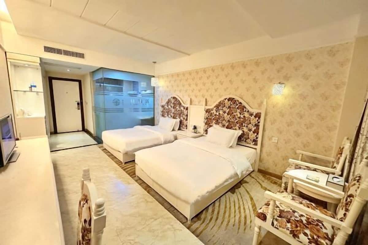Una habitación de hotel con dos camas, un escritorio, una silla y un baño.
