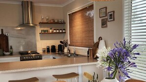 A modern kitchen with a central island, stainless steel appliances, and a hanging wicker light fixture.