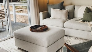A modern living room with a sofa, ottoman, and floor lamp.