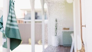 A covered outdoor shower with a copper pipe and a green towel hanging nearby. - Casa Billie ~ Family friendly beachside oasis (Aldinga Beach)