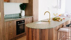A modern kitchen with a curved island, wooden cabinets, and a built-in oven. - Casa Billie ~ Family friendly beachside oasis (Aldinga Beach)