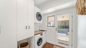 A compact laundry room with a washing machine, a drying machine, and a small window. - The Grape Escape~ Location & style on Shiraz Trail (McLaren Vale)