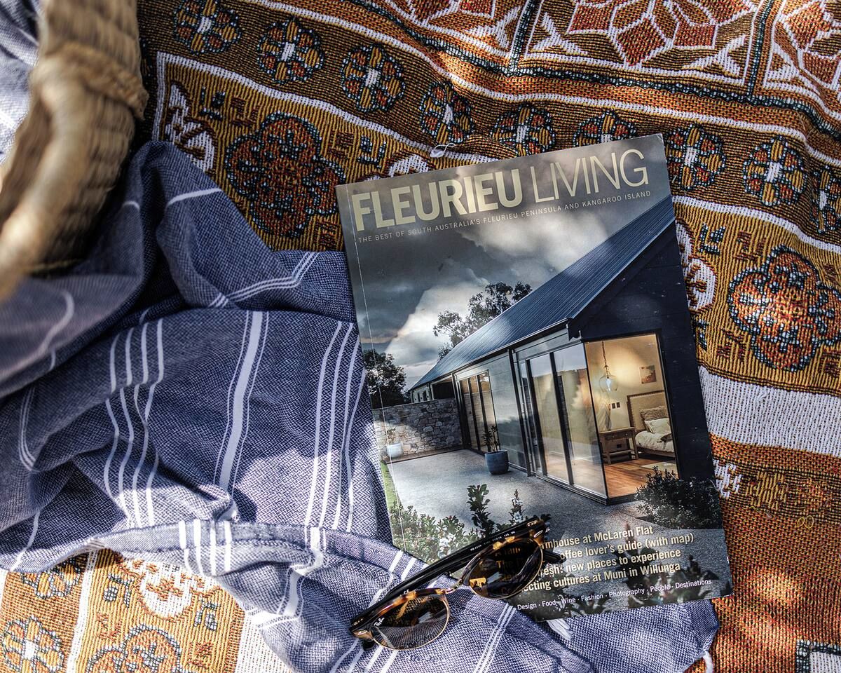 Ein Buch mit dem Titel 'Fleurieu Living' auf einem gemusterten Stoff, mit einer Illustration eines Hauses und einem Brillenpaar.
