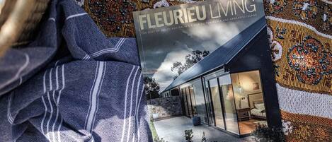 Ein Buch mit dem Titel 'Fleurieu Living' auf einem gemusterten Stoff, mit einer Illustration eines Hauses und einem Brillenpaar.