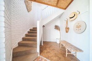 Un escalier avec un mur en briques blanches, un banc en bois et des décorations murales.