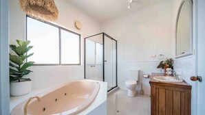 Un baño moderno con una bañera independiente, un inodoro, un lavabo con tocador de madera y un espejo grande.
