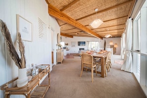A dining area with a wooden table set for four, surrounded by wicker chairs.