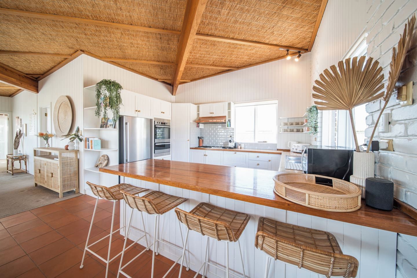 Een moderne keuken met een houten kookeiland, barstoelen en een grote ventilator.